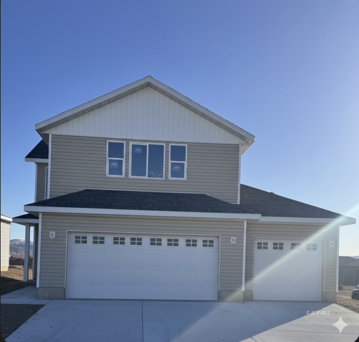 Two-story gray house with white trim, double garage, and separate single garage.