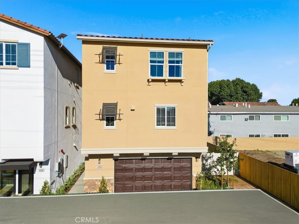 Three-story ochre home with a brown double garage door and tiled roof.