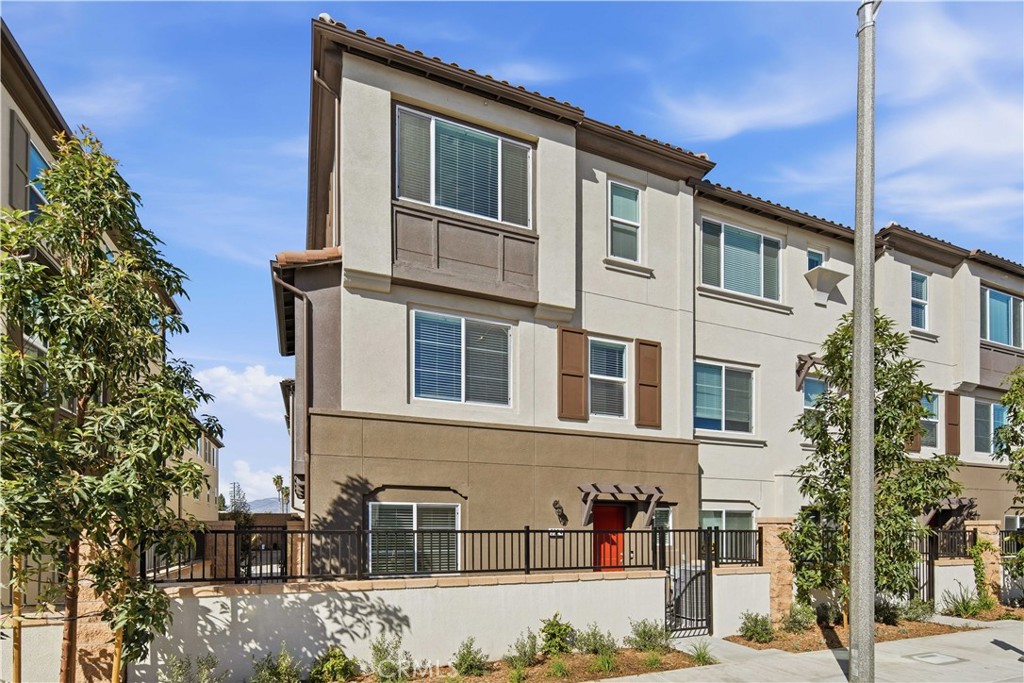 Multi-story townhouse with a red front door and fenced patio.
