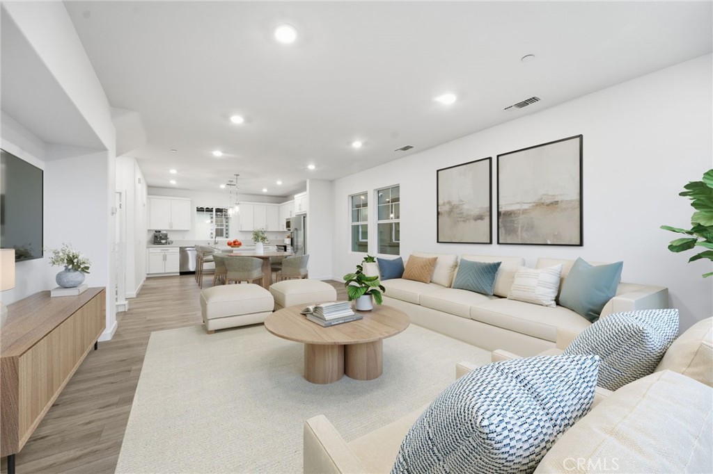 Open-plan living room with a cream sectional, round coffee table, and adjoining white kitchen.