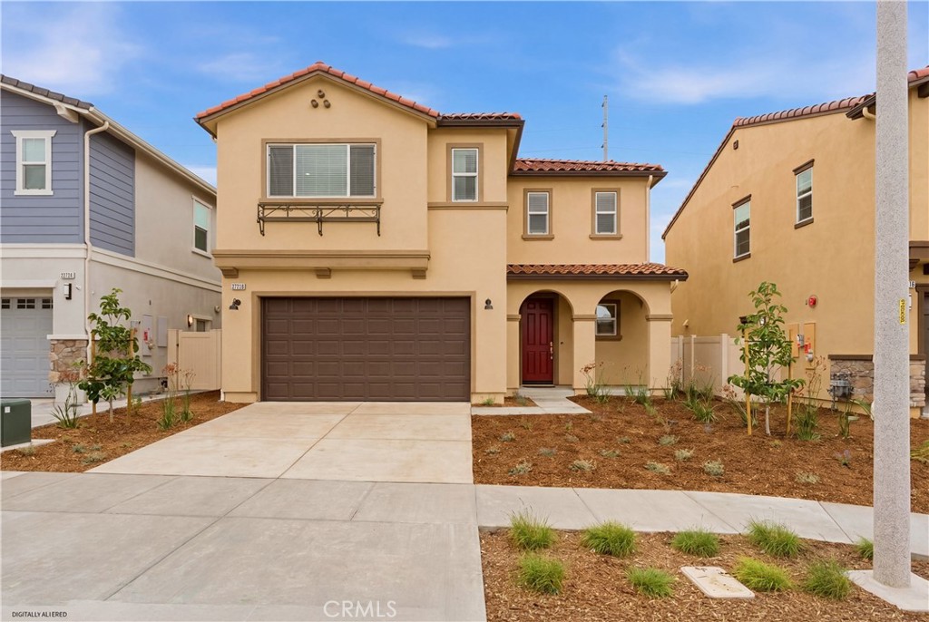 Two-story tan stucco house with a brown double garage door and arched front entry.