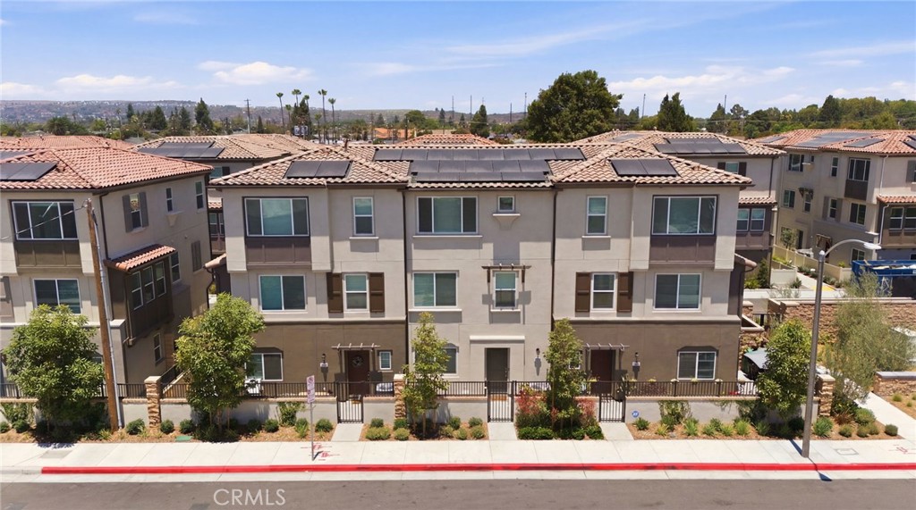 Multi-story townhomes with tiled roofs and rooftop solar panels, viewed from above.