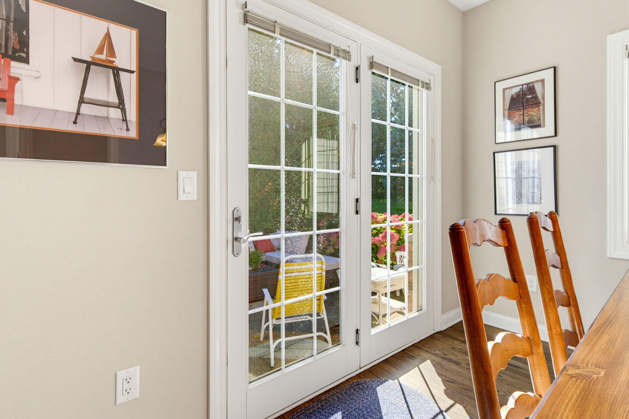 Dining room with white French doors opening onto a flower-lined patio.