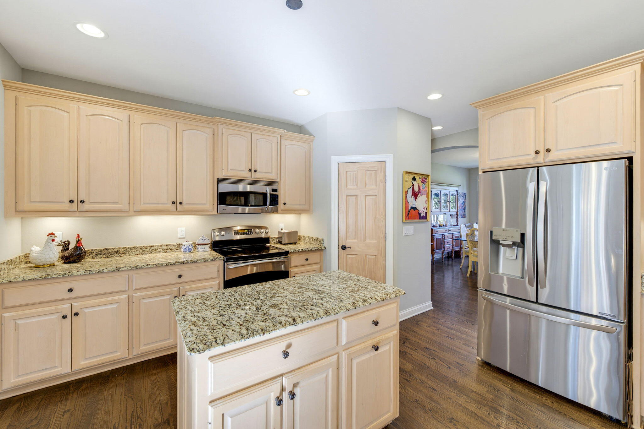 Kitchen with a granite-topped island, light wood cabinetry, and stainless steel appliances.