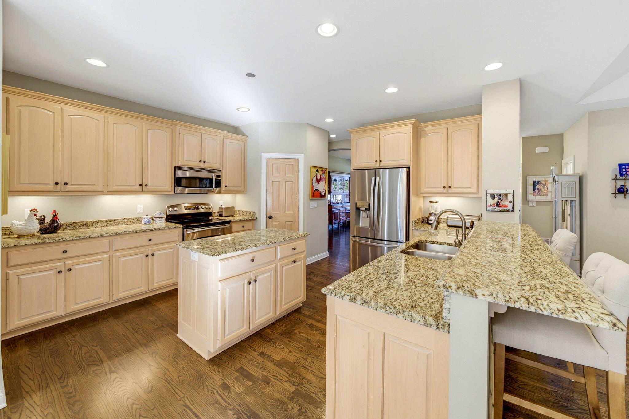 Kitchen with light wood cabinets, granite counters, stainless steel appliances, and hardwood floors.
