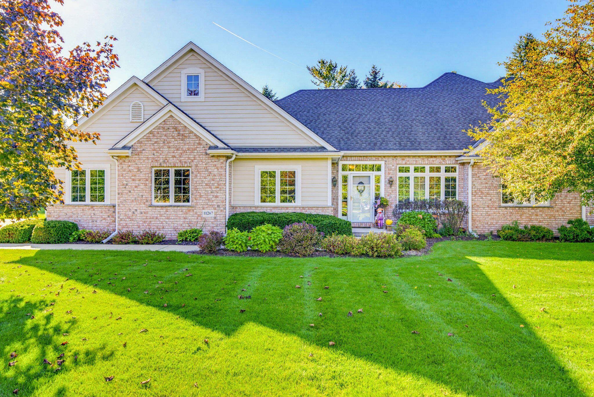 House with brick and light siding, gabled roof, and landscaped front lawn.