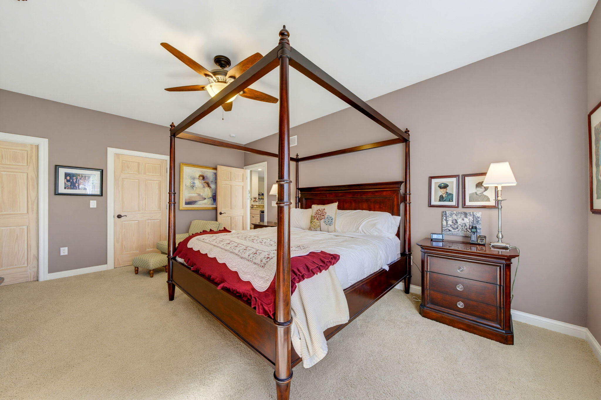 Bedroom with a dark wood four-poster bed, white bedding, and a red quilt.