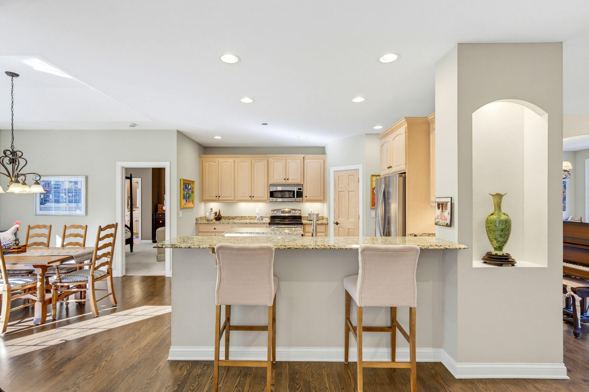 Kitchen with a large granite island, light wood cabinets, stainless steel appliances, and an adjoining dining area.