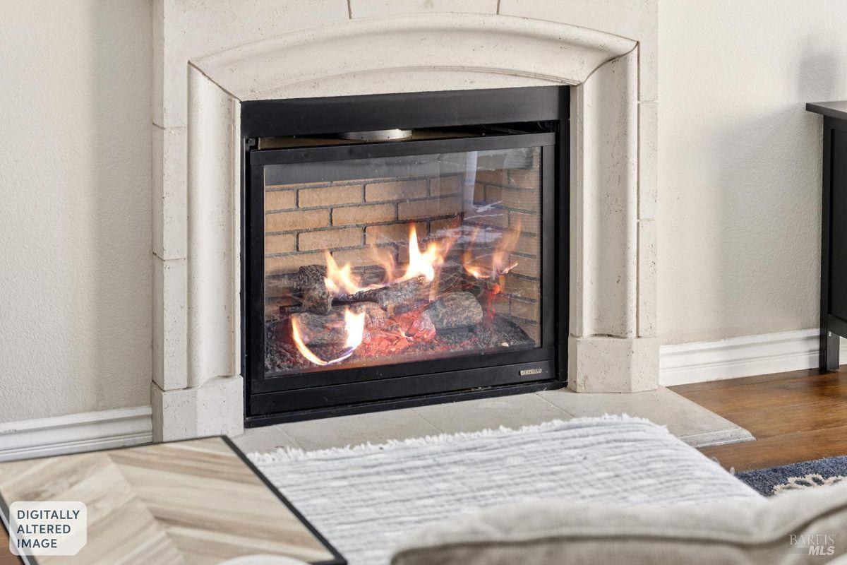 Lit glass-front fireplace with a pale stone surround and rug in the foreground.