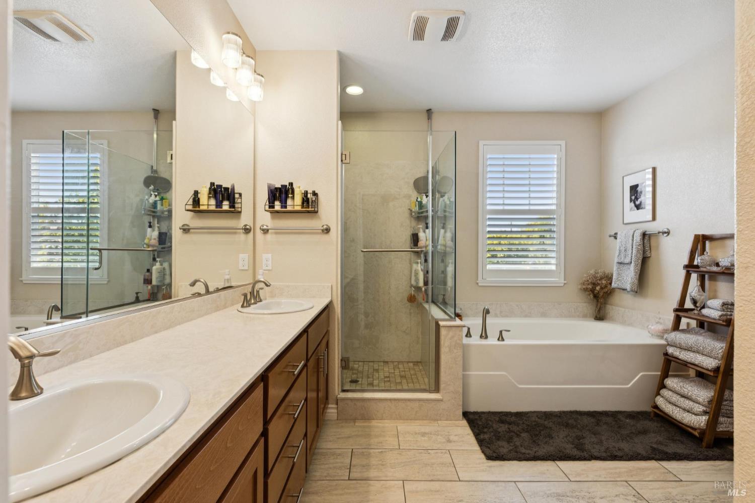 Bathroom with a long vanity, glass shower, and soaking tub.
