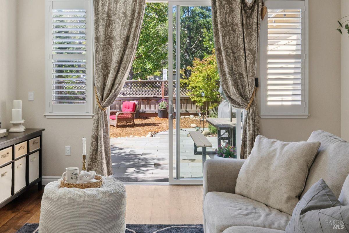Living room with a gray sofa and sliding doors opening onto a patio and leafy backyard.