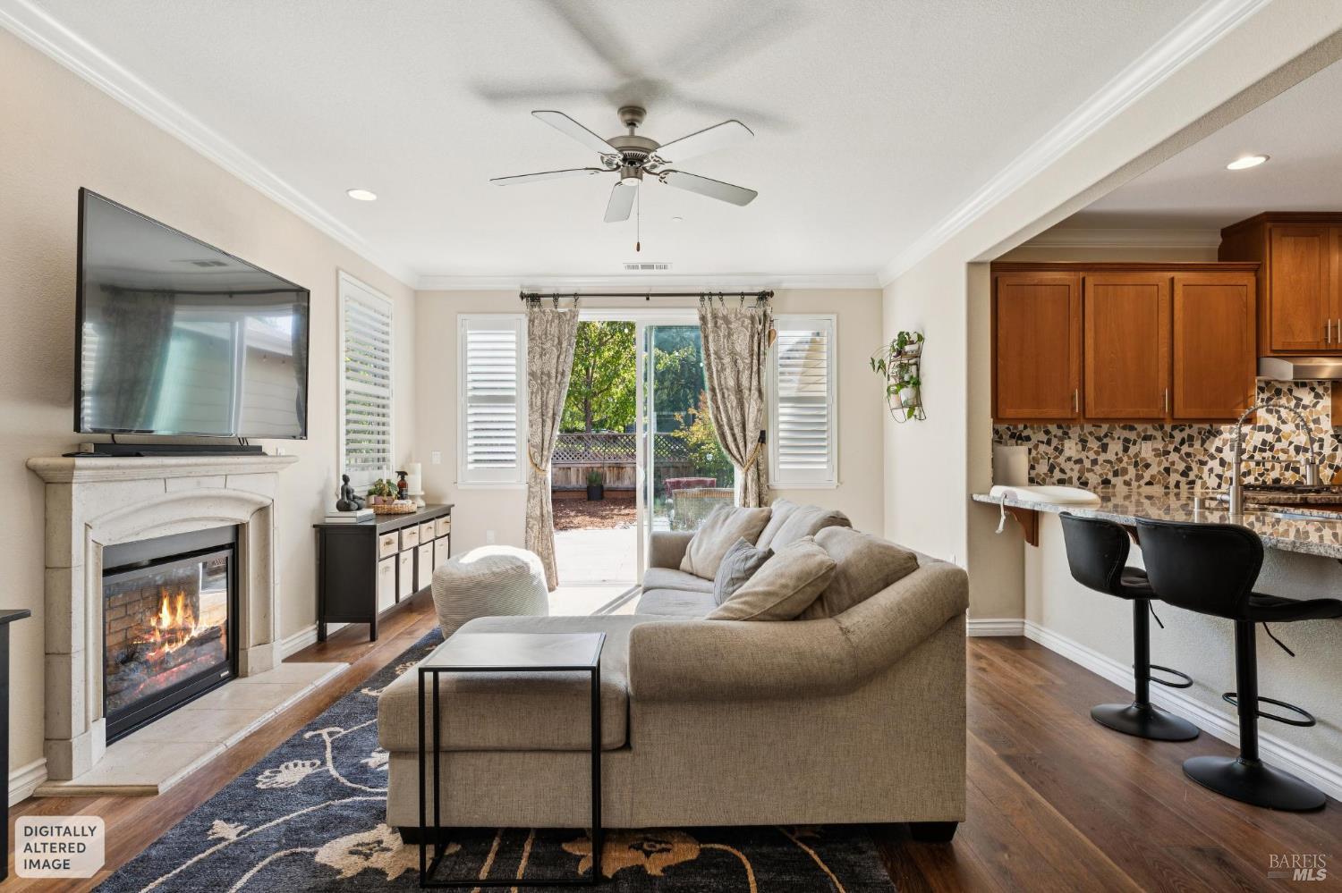 Living room with a beige sectional, lit fireplace, and sliding doors opening to a garden patio.