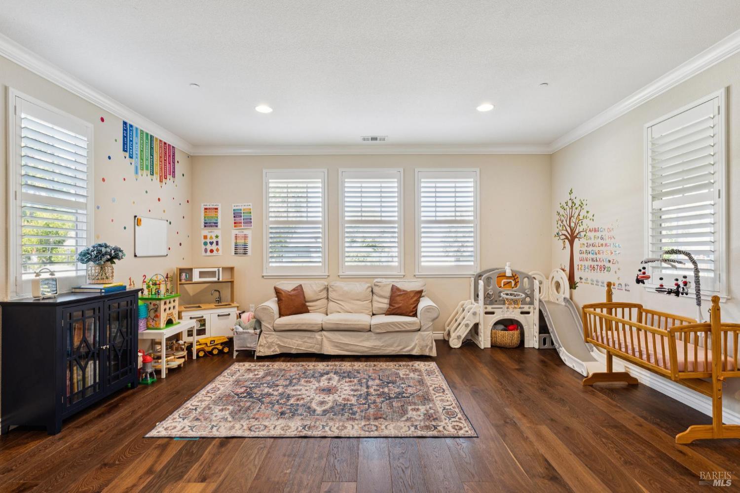 Playroom with a sofa, children’s toys, indoor slide, and shuttered windows.