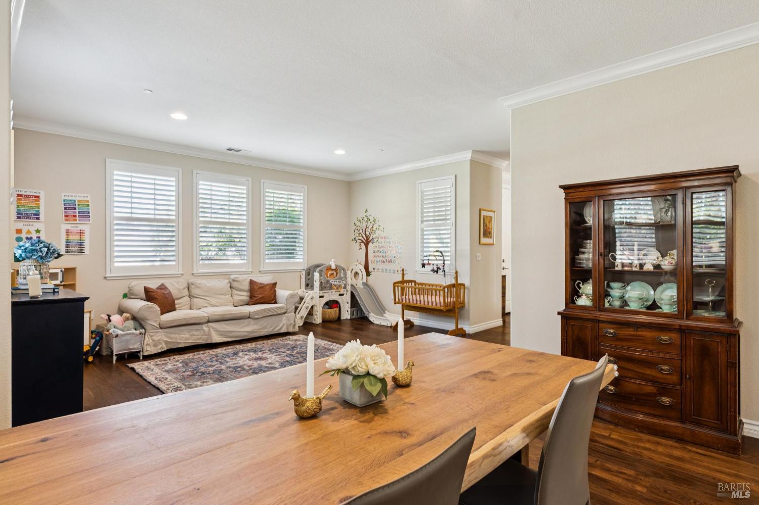 Dining room with a long wooden table and china cabinet beside a bright play area with a slide and swing.
