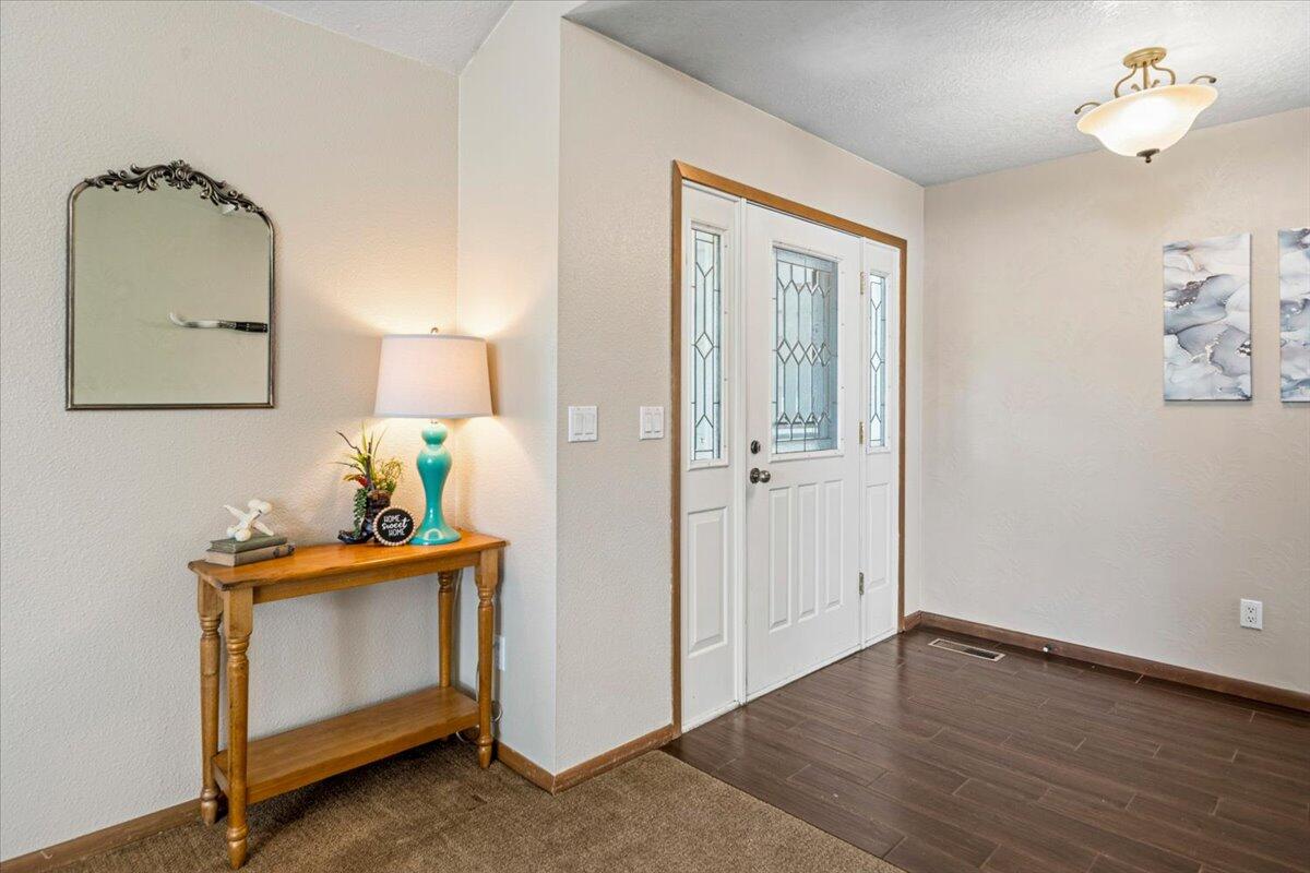 Entryway with a white decorative-glass front door and a wooden console table beneath an ornate mirror.