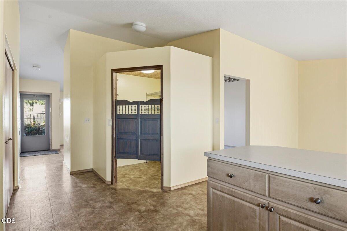 Kitchen with a broad cabinet counter, patterned tile floor, and dark swinging doors in the adjoining doorway.