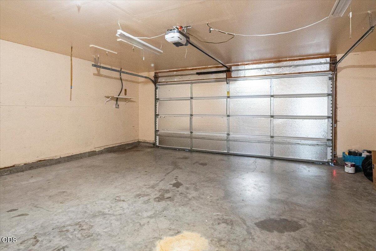 Empty garage with a closed overhead door and stained concrete floor.