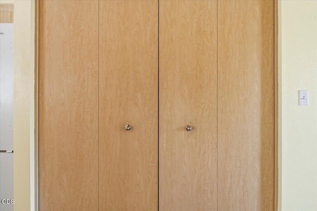 Tall light wood cabinet doors with round metal knobs beside a refrigerator.
