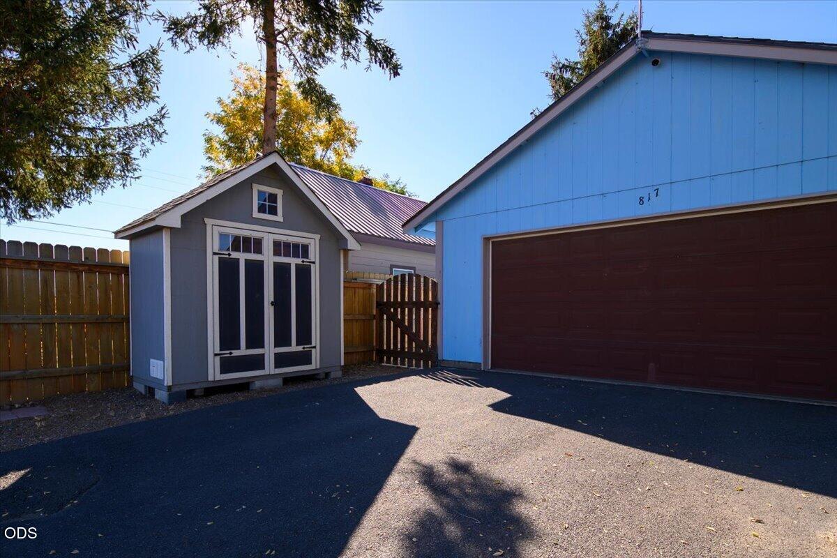 Blue detached garage with a dark-brown door beside a gray storage shed.