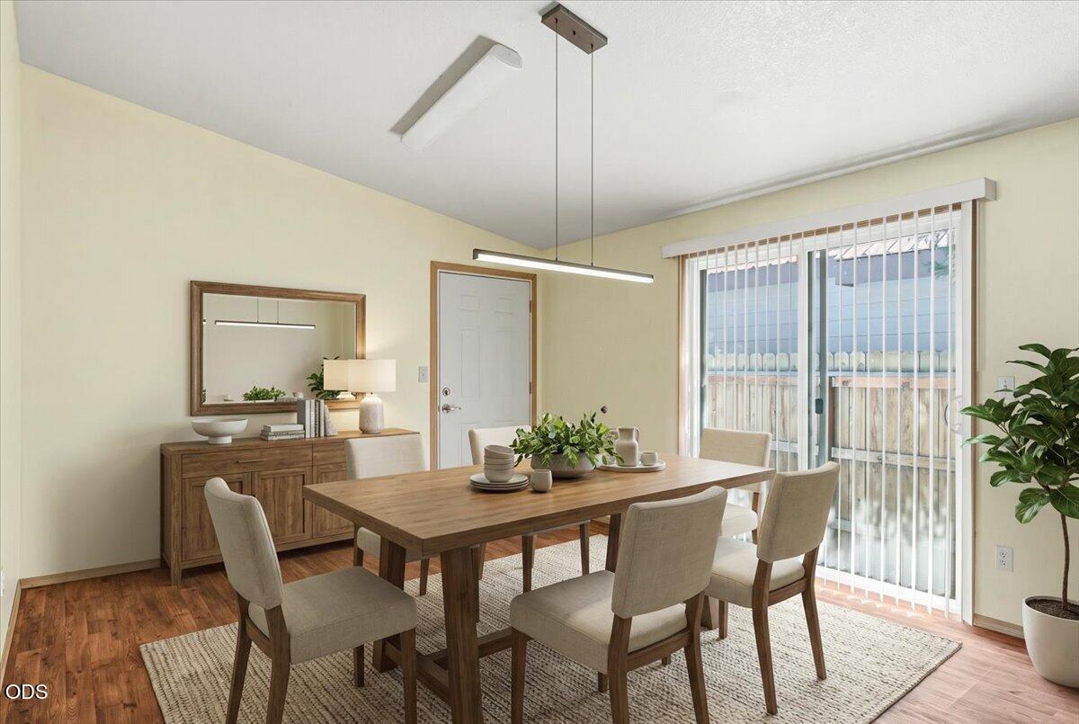 Dining room with a wooden table, upholstered chairs, sideboard, and sliding glass doors.
