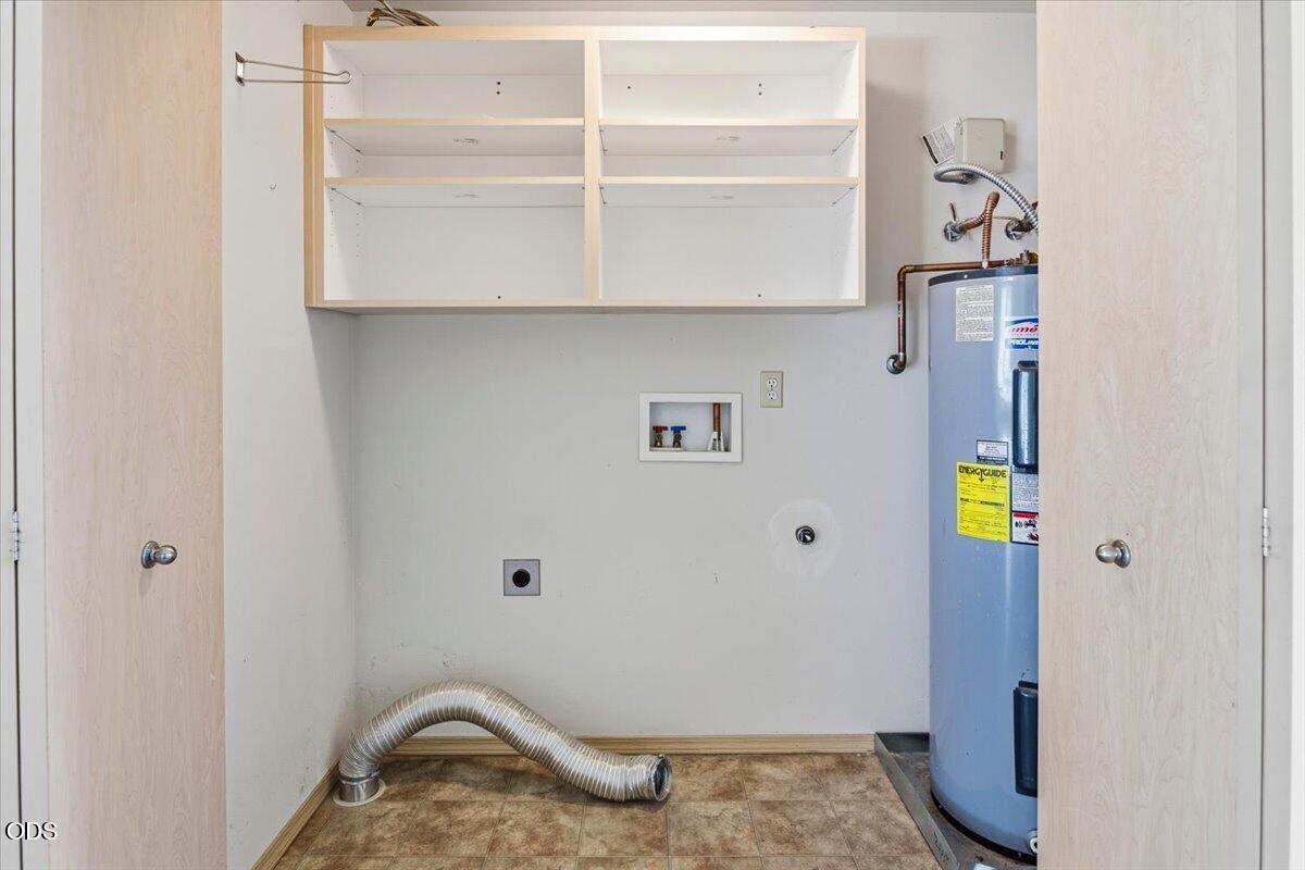 Laundry utility room with open shelves, washer hookups, and a water heater.