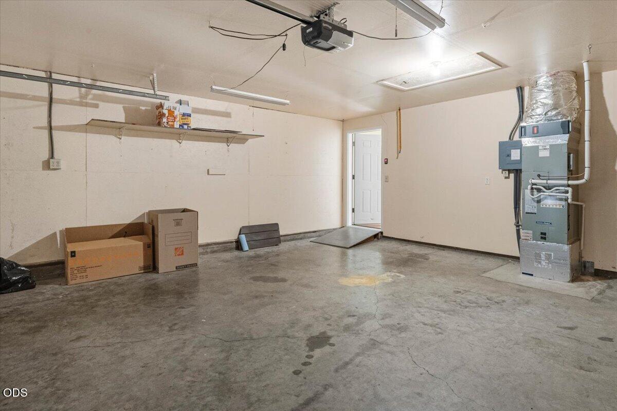 Garage with a concrete floor, wall shelving, and heating and cooling equipment.