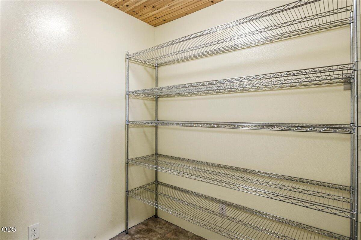 Storage closet with extensive metal wire shelving and a wood-plank ceiling.