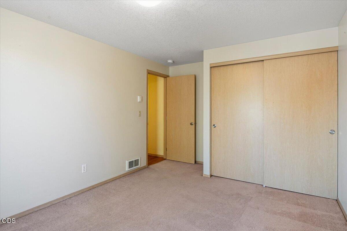 Empty bedroom with beige carpet and a large sliding wood closet.