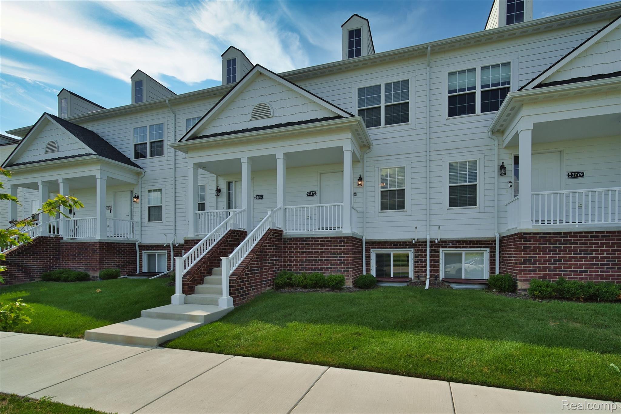White townhouse exterior with covered porches, brick foundations, and front steps.