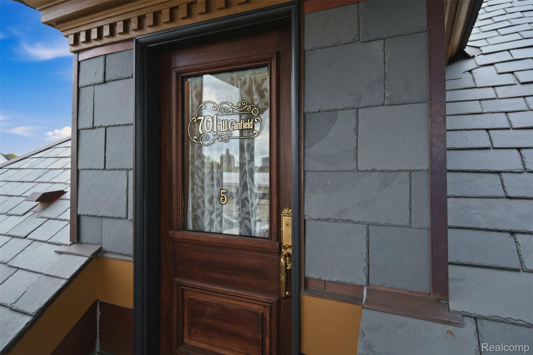 Unit 5 entrance door with a decorative 701 W. Canfield plaque and brass hardware.