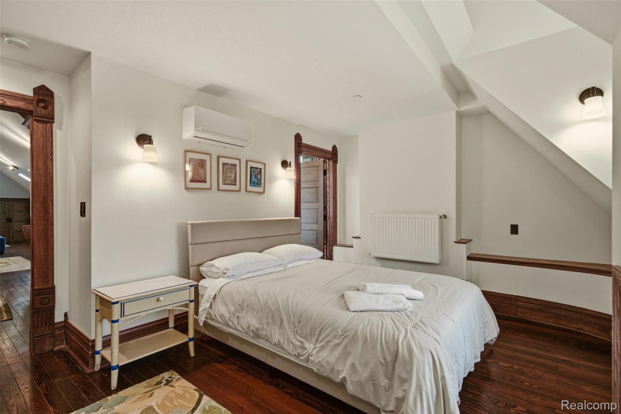 Bedroom with a white bed, ornate dark wood trim, and a sloped ceiling.
