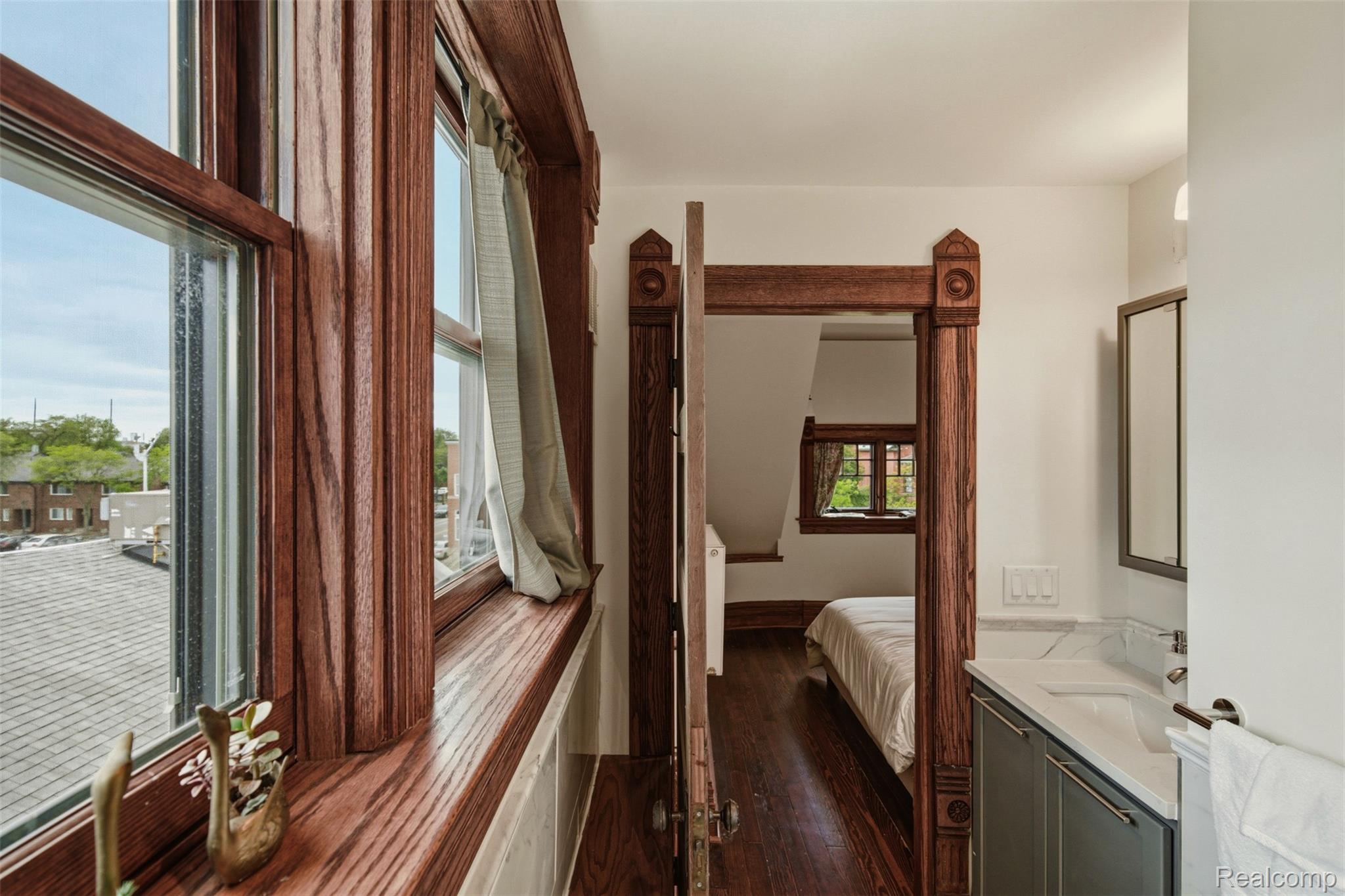Bedroom and bathroom with ornate wood trim, a window seat, and a compact white vanity.