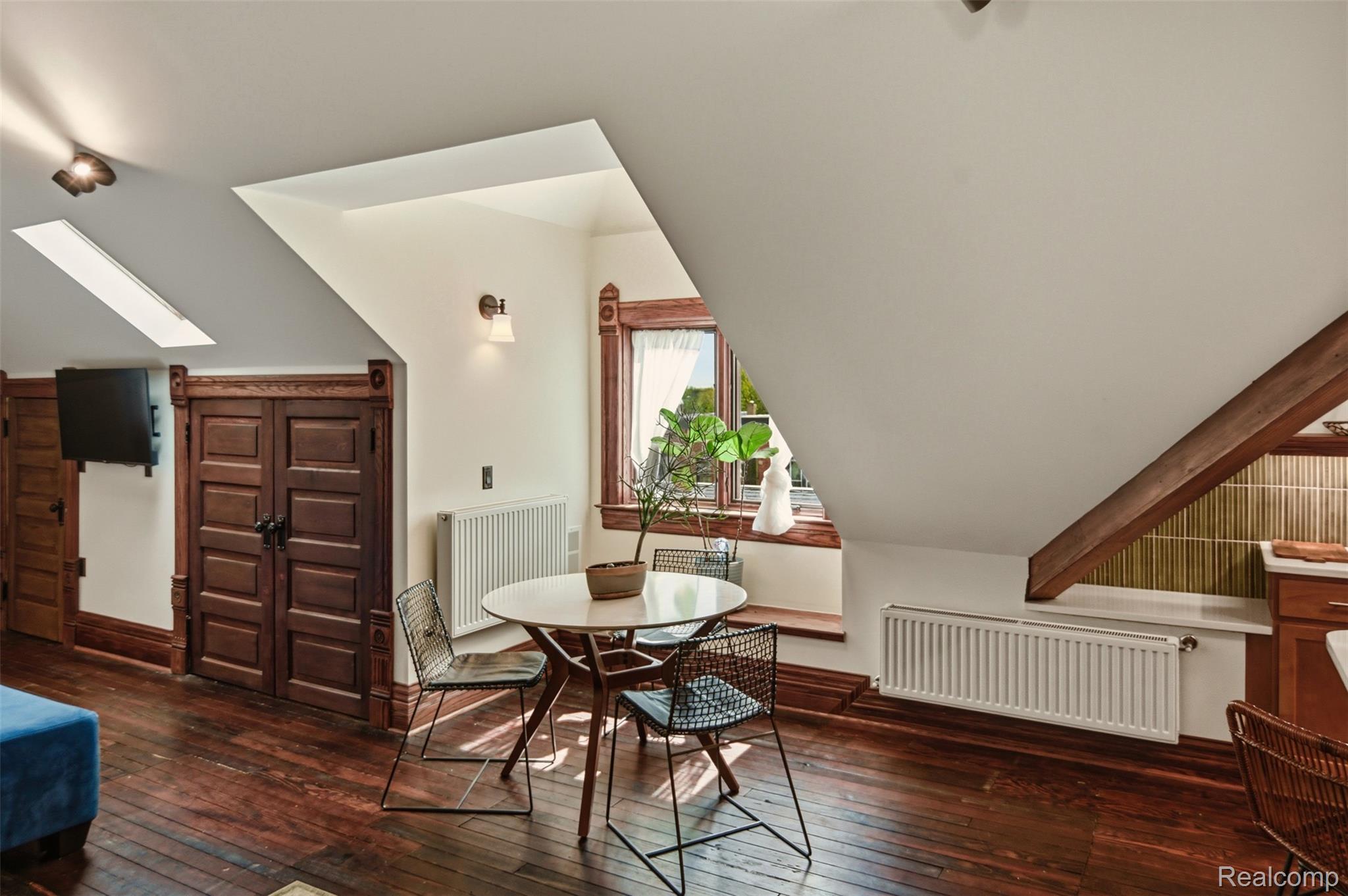 Attic dining area with a round table, skylights, sloped ceiling, and ornate wood trim.