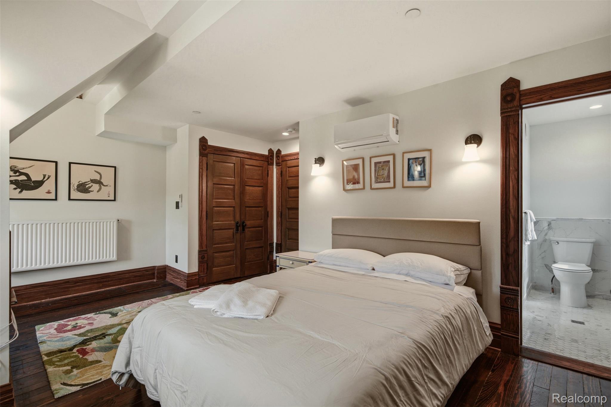 Bedroom with a large bed, ornate dark wood trim, and an adjoining bathroom.