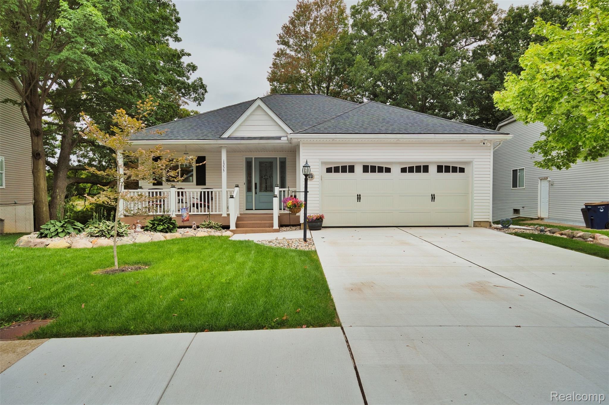 White single-story home with a covered porch, two-car garage, and wide driveway.