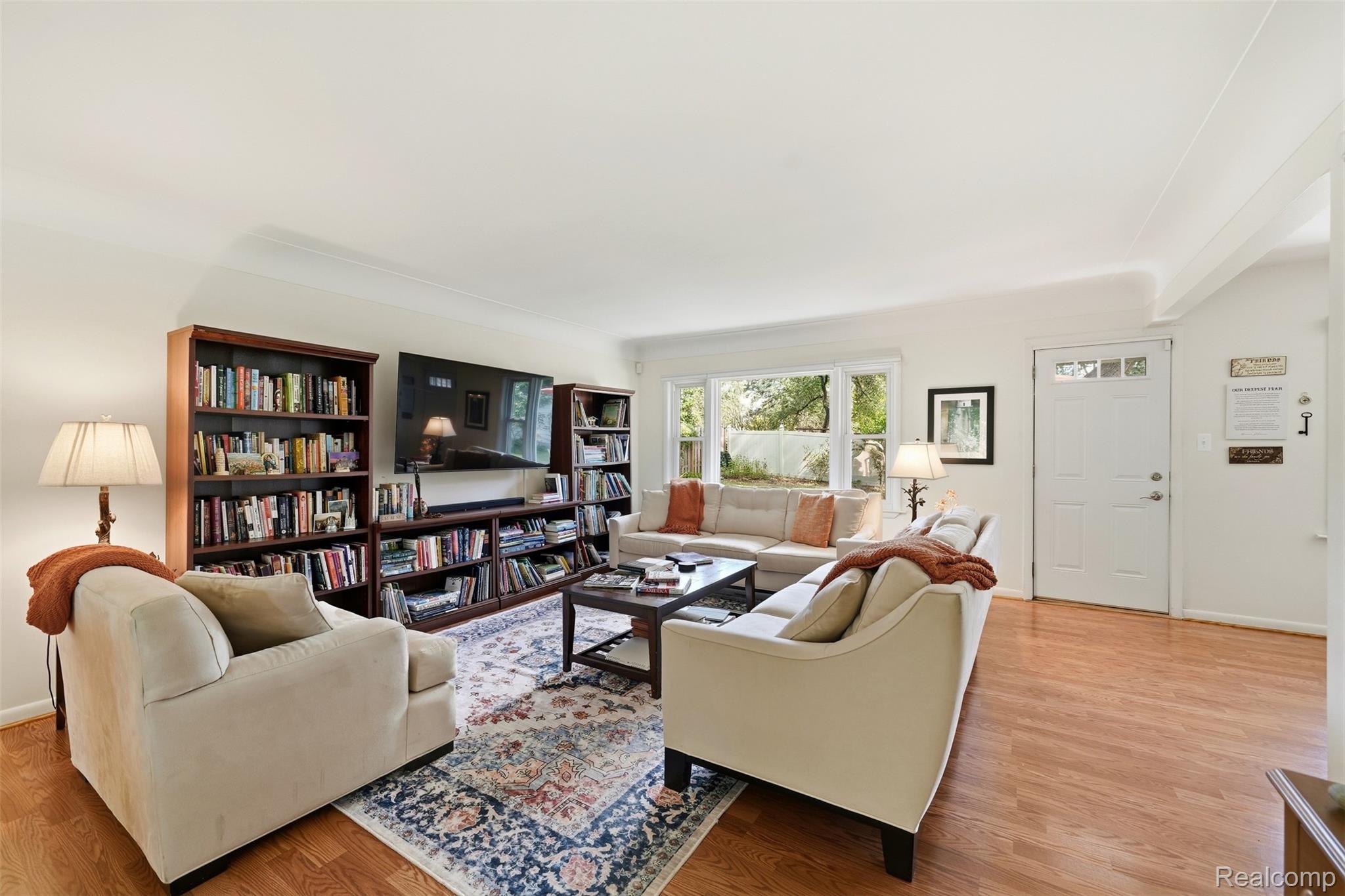 Living room with cream sofas, tall bookcases, a television, and large windows.