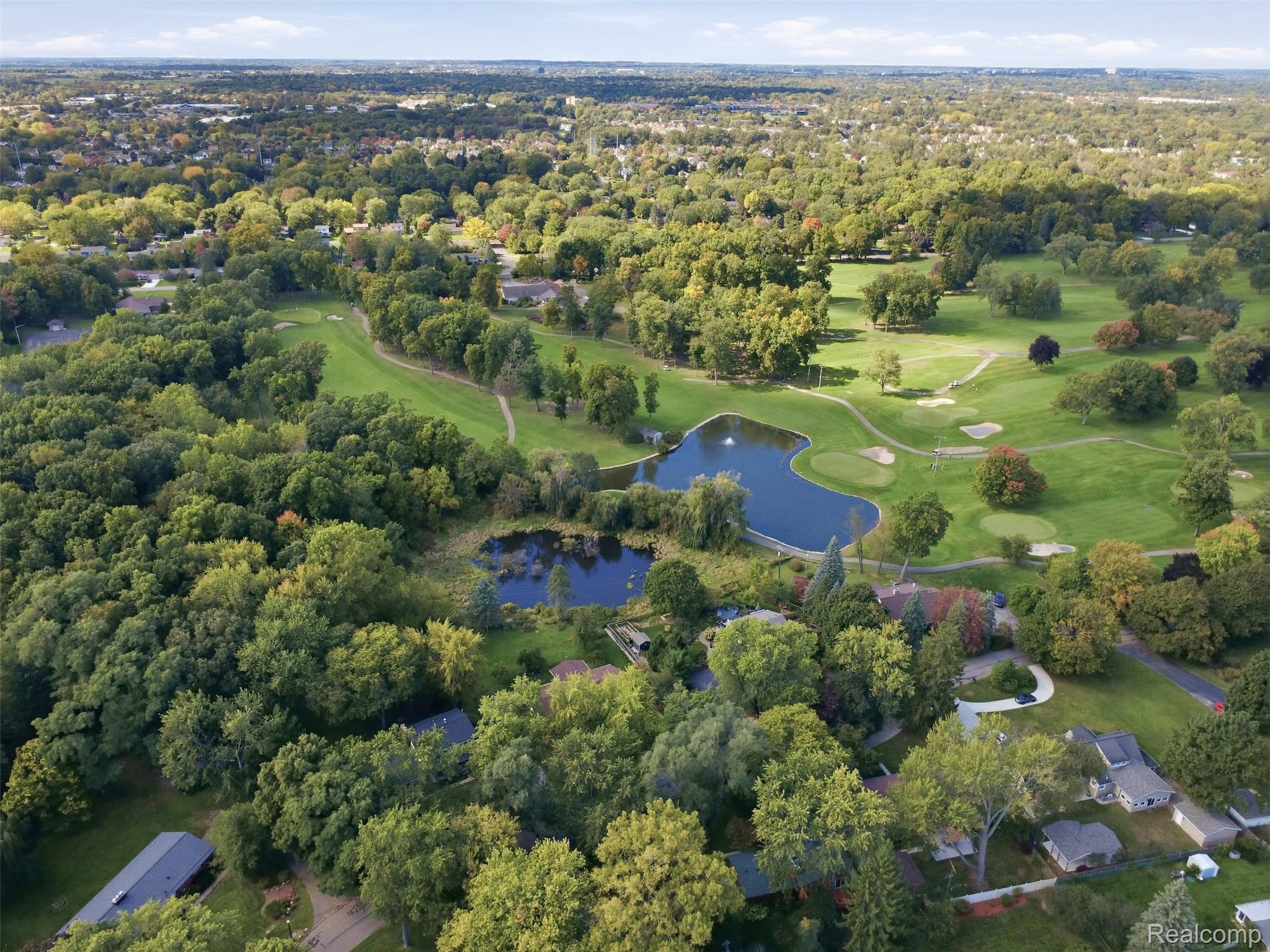 Aerial view of a residential neighborhood beside a golf course with ponds and tree-lined greens.