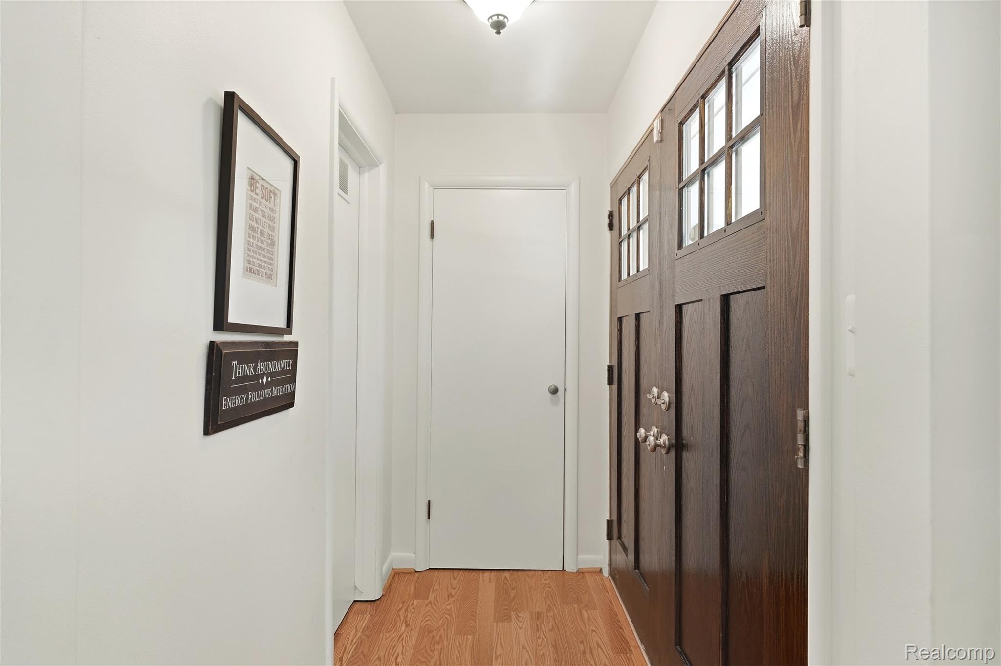Home entryway with a dark wood, glass-paneled front door and light wood flooring.