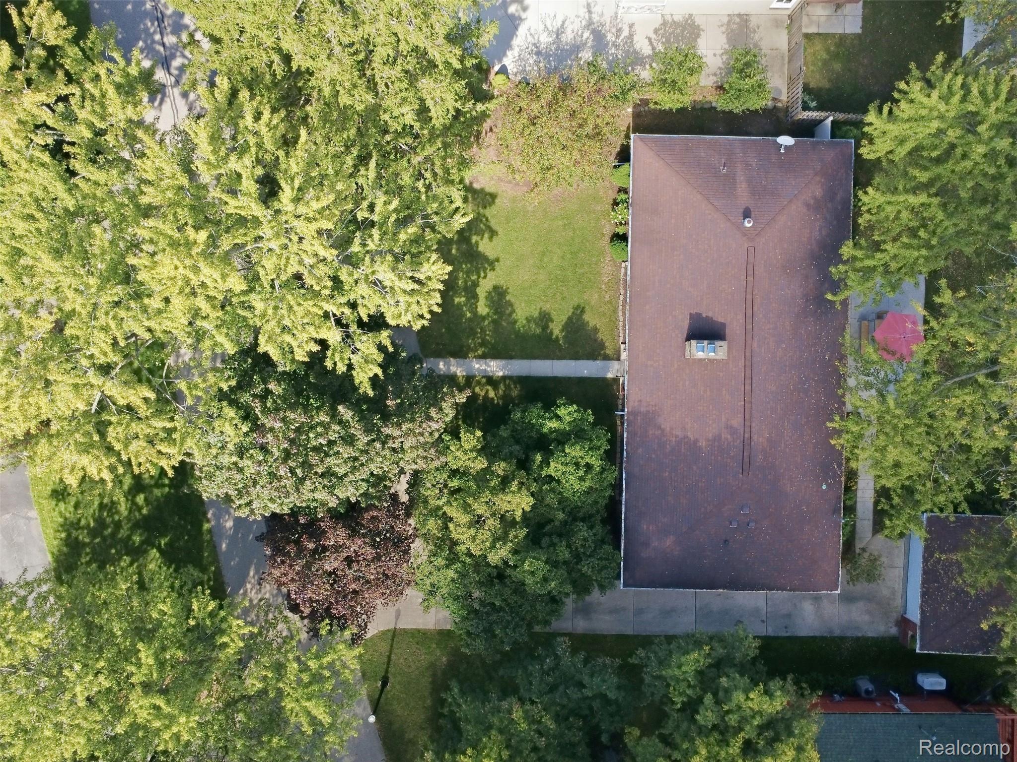 Aerial view of a house and leafy yard with paved walkways.