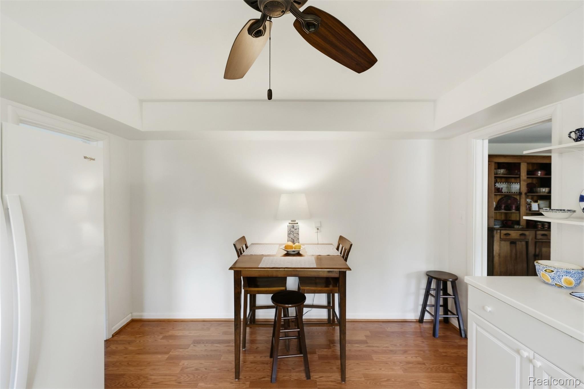 Dining area with a wooden table and chairs, hardwood floors, and a ceiling fan.
