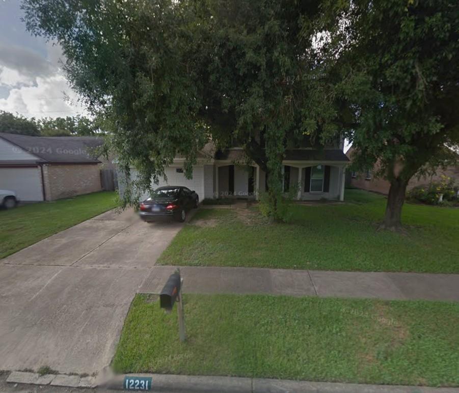 Front exterior of 12231 Fetlock Drive, partly shaded by a large tree, with a driveway and parked car.