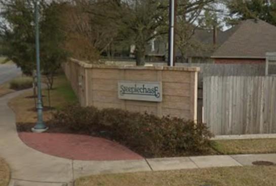 Steeplechase neighborhood entrance sign beside a sidewalk and landscaped brick wall.