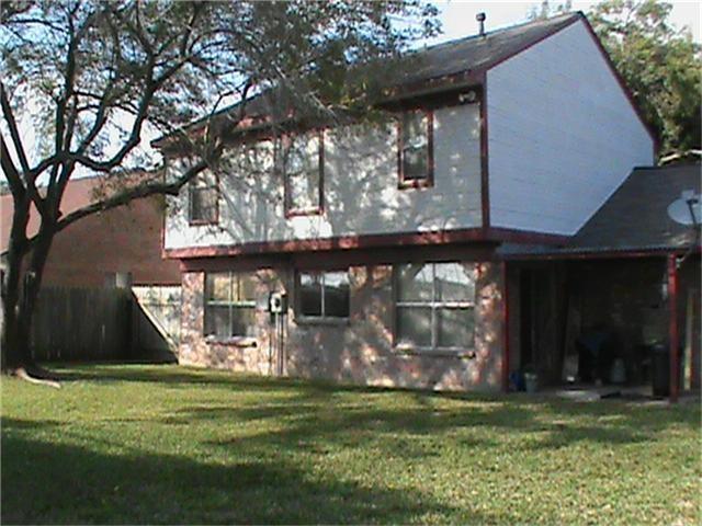 Two-story house with brick and white siding, a covered patio, and a shaded grassy backyard.