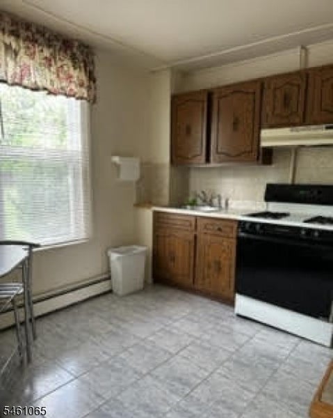 Kitchen with dark wood cabinets, a black-and-white stove, and a large window with floral valance.