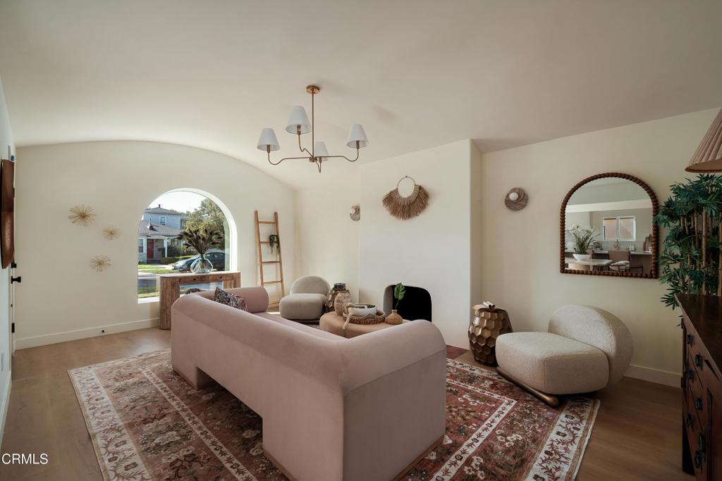 Staged living room with a curved pink sofa, patterned rug, and large arched window.
