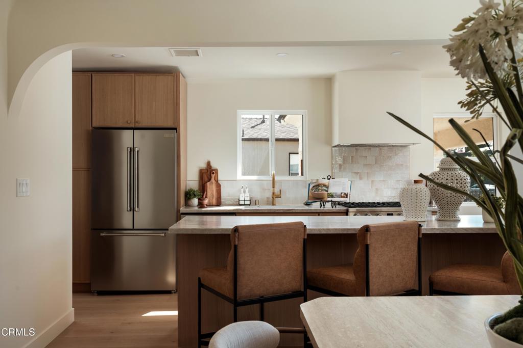 Kitchen with a large island, stainless steel refrigerator, wood cabinetry, and counter seating.