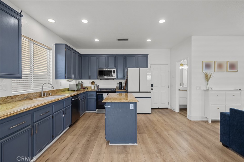 Kitchen with blue cabinets, granite counters, central island, and light wood flooring.