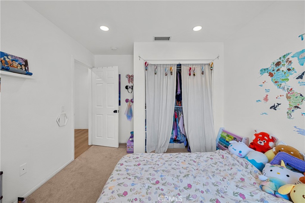 Bedroom with a curtained open closet, colorful world map decal, and stuffed animals.