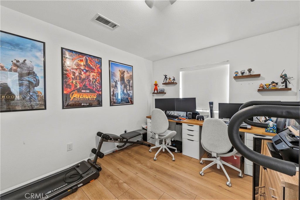 Home office with dual computer workstations, movie posters, collectibles, and exercise equipment.
