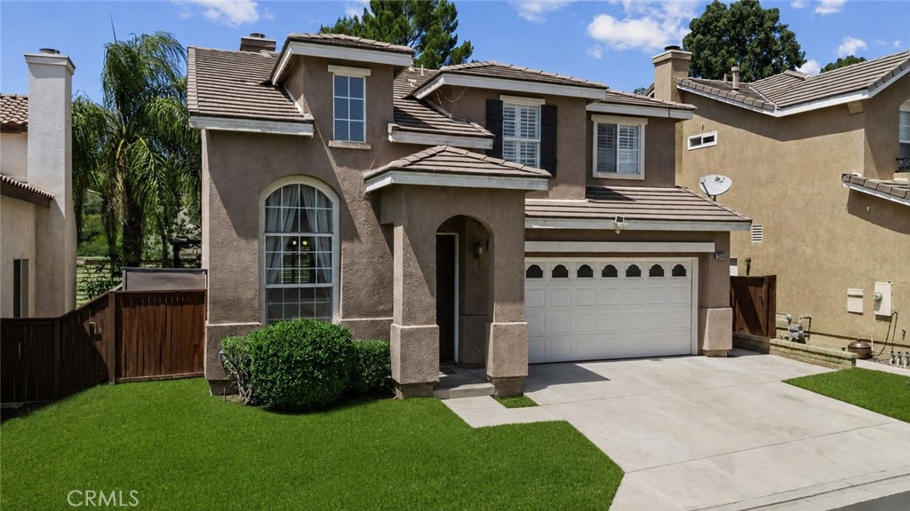 Two-story stucco house with a tiled roof, arched entry, and attached two-car garage.